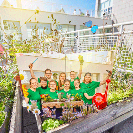 Eine Gruppe junger Menschenn in grünen T-Shirts in einem Pflanzenumfeld 